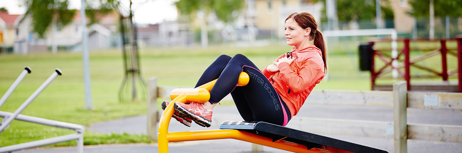 A woman is exercising on a workout bench, she is doing crunches. 